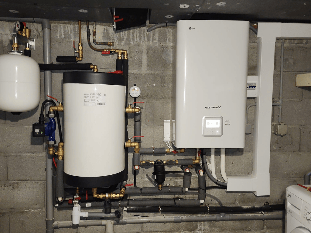 Installation intérieure de pompe à chaleur air/eau avec ballon d’eau chaude et unité murale dans un local technique résidentiel.